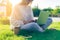 Cropped adult Woman texting laptop, sitting on the grass outside in park. Working and drinking coffee. Using laptop and mobile