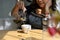 Cropped, aged woman poring hot coffee into a ceramic cup on the table