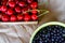 Cropped bowl of blueberries and box, crape of red sweet cherries with tail on craft wrinkled old paper background