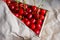 Cropped box, crape of sweet red cherries with tail on craft wrinkled paper background covered. Summer fruits and berries