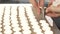 Cropped close up of a confectioner using pastry bag preparing meringue cookies