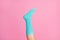 Cropped close-up view of one nice single leg wearing blue soft cotton bright sock isolated over pink pastel color