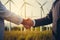 Cropped closeup of a handshake between two businessmen with a wind turbines background