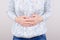 Cropped closeup photo of unhappy sad upset woman holding hands on tummy suffering from indigestion isolated grey background