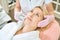 Cropped female cosmetologist doing laser depilation of face of adult woman