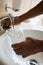 Cropped hands of man filling drinking glass at sink