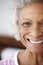 Cropped Head And Shoulders Portrait Of Smiling Senior Woman Sitting On Bed At Home Looking Positive