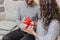 Cropped image of affectionate guy giving present his girlfriend while sitting on the sofa in new year time.