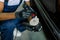 Cropped image of African man, auto service worker, wearing white t-shirt and blue overalls, putting special polish wax