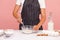 Cropped image of baker in black striped apron mixing dough with corolla, making bakery, homemade pastry, confectioner preparing