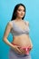 Cropped image of beautiful pregnant woman hugging her tummy with pink ribbon