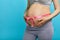 Cropped image of beautiful pregnant woman hugging her tummy with pink ribbon