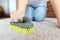 Cropped image of beautiful young woman using a brush while cleaning a beige carpet