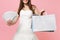 Cropped image of bride woman in wedding dress holding bundle lots of dollars cash money, multi colored packages bags