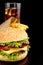 Cropped image of cheeseburger,french fries,glass of cola on black