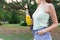 Cropped image of a cute girl who is having a walk in the park holding a bottle of orange juice in a sunny warm day