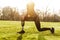 Cropped image of disabled athletic girl in black sportswear, doing lunges and stretching prosthetic leg on grass