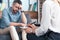 cropped image of female counselor writing in clipboard while depressed male patient sitting on sofa