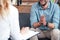 cropped image of female counselor writing in clipboard and smiling male holding hand palms together during therapy session