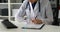 Cropped image of female doctor typing on keyboard and filling documents.