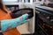 Cropped image of girl holding container with cake by oven