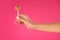 cropped image of girl holding lollipop in hand isolated on pink