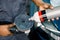 Cropped image of hands of African male auto service worker, putting special polish wax or cream on the orbital polish