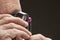 Cropped image of jeweler examining jewel over black background