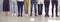 Cropped image of legs of different men and women standing in row in bright room.