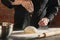 Cropped image of male chef, cook in black kitchen uniform make bread dough at cafe, restaurant kitchen. Concept of