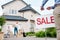 cropped image of male realtor with sale signboard and family with cardboard boxes