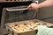 Cropped image of man hands putting a tray with seasoned sliced king trumpet mushrooms pleurotus eryngii in oven