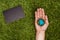 cropped image of man holding earth model on hand, blackboard on green grass, earth