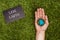 cropped image of man holding earth model in hand with sign save earth on green grass, earth