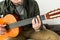 cropped image of man playing barre chord on acoustic guitar