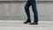 Cropped image man walking in black shoes. Closeup male feet going near building