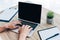 cropped image of man working with laptop at table with potted plant, empty clipboard