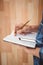 Cropped image of man writing on diary with pencil