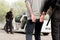 cropped image of policewoman walking with criminal in handcuffs while partner waiting them