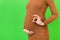 Cropped image of positive pregnant woman in brown dress showing okay gesture against her belly at green background. Easy and happy