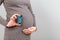 Cropped image of pregnant woman holding asthma inhaler to prevent attack at colorful background with copy space. Future mother is