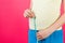 Cropped image of pregnant woman in home clothing measuring her growing abdomen at pink background. Inch tape measure. Copy space