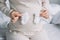 cropped image of pregnant woman touching belly with newborn shoes in bedroom