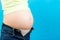 Cropped image of pregnant woman in unzipped jeans showing her baby bump at colorful background with copy space. Waiting for a baby