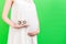 Cropped image of pregnant woman in white dress showing thirty weeks of pregnancy cubes at green background. Waiting for a baby.