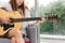 Cropped image of relaxed young Asian woman playing acoustic guitar in living room