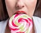 Cropped image of seductive girl biting colorful lollipop. Valentines day concept