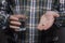 Cropped image of a sick person holding a tablet and a glass of water, on a gray background, hands of a working man