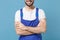 Cropped image of smiling young man in coveralls isolated on pastel blue background studio portrait. Instruments