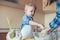 cropped image of son and mother kneading dough